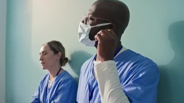 Koridorda Durmuş Koruyucu Maskeleri Çıkartıp Hakkında Tartışan Iki Yorgun Doktorun — Stok video