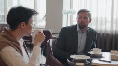 Genç Asyalı adamın seçici odağı ve Kafkasyalı iş arkadaşı modern restoranda oturmuş iş planını tartışıyorlar.