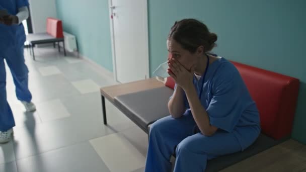 手術後に休憩している廊下のベンチに座っている疲れた女性医師の手持ちの肖像画 — ストック動画