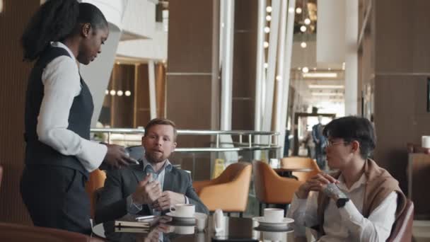 Két Etnikailag Változatos Üzletember Asztalnál Hotel Éttermében Projektről Beszélgetnek Egyikük — Stock videók