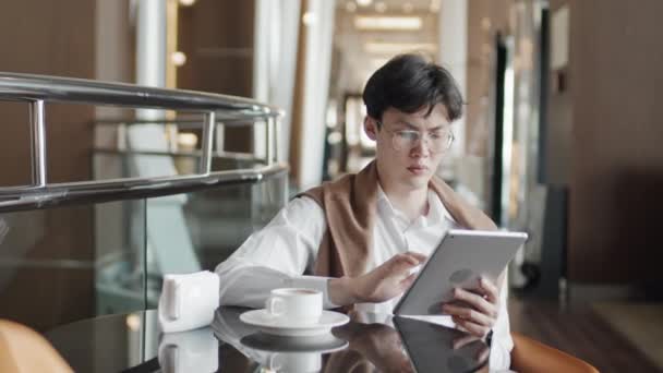 Poważny Młody Azjatycki Biznesmen Okularach Siedzi Hotelowej Restauracji Pracuje Tablecie — Wideo stockowe