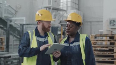 Etnik çeşitlilikte kadın ve erkeğin mermer fabrikasında birlikte çalıştığı orta boy portresi dijital tablet verilerini kontrol ediyor ve sorunları tartışıyor.