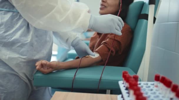女性の血液ドナーのためのカヌーとIvチューブを固定する認識できない医療従事者の選択的な焦点 — ストック動画