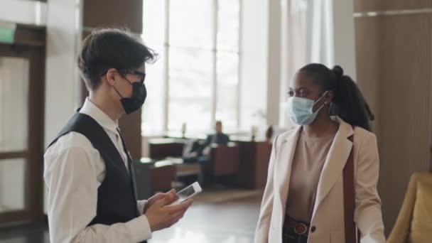 Koruyucu Maske Takan Genç Kapıcı Elinde Dijital Tabletle Otel Müşterisiyle — Stok video