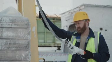 Kafkas erkek fabrika işçisi ağır çantaları taşımak için kaldırma kolu kullanıyor.