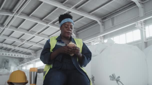 Vista Ángulo Bajo Mujer Afroamericana Ropa Trabajo Sentada Almacén Comiendo — Vídeos de Stock