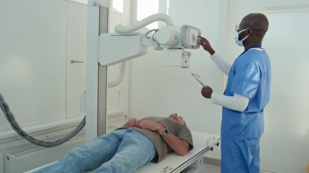 Afroamerikanischer Professioneller Radiologe Passt Einstellungen Des Röntgenscanners Für Seinen Patienten — Stockvideo