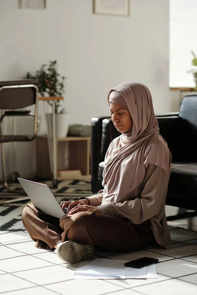 Jonge Moslim Vrouw Hoofddoek Zittend Vloer Van Woonkamer Netwerken Terwijl — Stockfoto