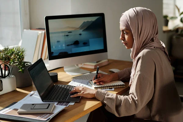 Joven Empresaria Musulmana Seria Mirando Pantalla Computadora Portátil Tomando Notas —  Fotos de Stock