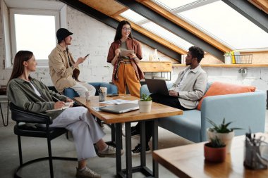 Gündelik giysiler içinde genç kültürler arası profesyoneller başlangıç toplantısında beyin fırtınası yaparken çalışma noktaları ve yeni fikirler hakkında tartışıyorlar.