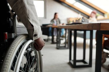 Genç Afro-Amerikan iş adamının yakın çekimi tekerlekli sandalyeyle iki meslektaşının iş organize ettiği yere doğru ilerliyor.