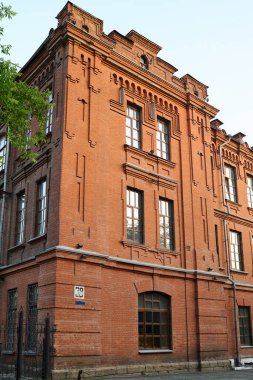 Modern şehrin eski bölümünde kameranın önünde duran üç katlı terk edilmiş kırmızı tuğlalı evin köşesinde.