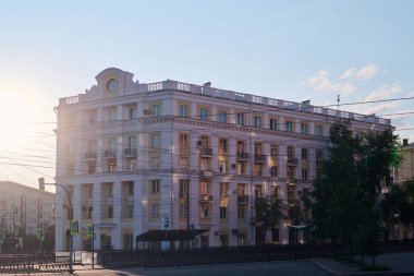 Modern şehrin merkez caddesinde klasik tarzda inşa edilmiş çok katlı bir ev. Güneşli yaz gününde dökme demir çit ve yol boyunca.