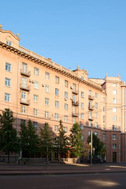 Modern şehrin merkezinde yol boyunca duran yeşil ağaçlarla çevrili belediye binasının veya apartmanların bir kısmı.