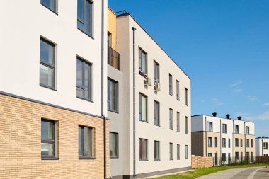 Kentsel olmayan bölgenin merkez caddesinde pencereleri olan üç katlı uzun beyaz apartmanların perspektifi