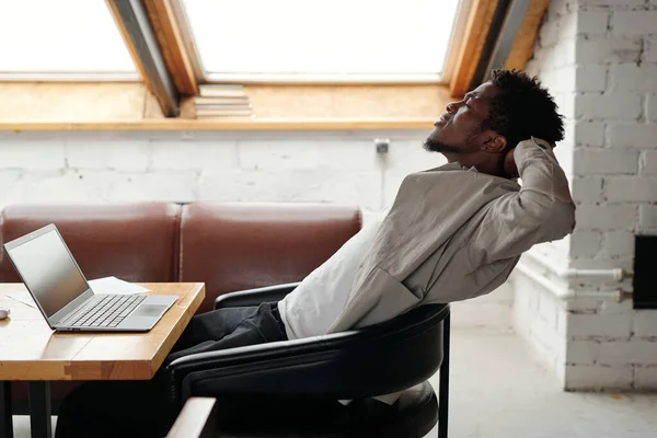 Mladý Přepracovaný Afroamerický Podnikatel Sedí Koženém Křesle Před Notebookem Kanceláři — Stock fotografie
