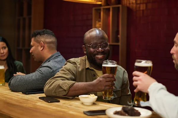 Uomo Sorridente Che Guarda Bicchiere Birra Mentre Siede Davanti Suo — Foto Stock