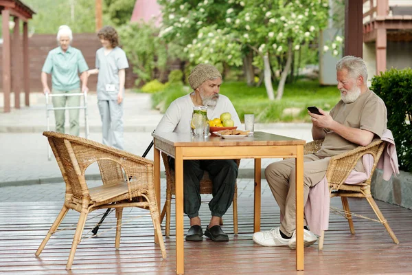Dois Homens Seniores Sentados Confortáveis Poltronas Vime Por Mesa Madeira — Fotografia de Stock