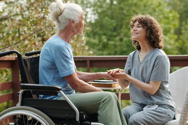 Üniformalı Genç Bakıcı Engelli Yaşlı Kadına Bakıyor Tekerlekli Sandalyede Oturuyor — Stok fotoğraf