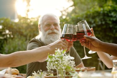 Aile üyelerinin akşam yemeği için ev yapımı yemekle servis edilen masada kadeh kaldırma töreninde kırmızı şaraplı birkaç şarap kadehine odaklanın.