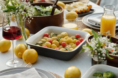 Patates ve domatesli servis masasının bir kısmı taze portakal suyu, bir bardak kırmızı şarap ve diğer şeylerin ortasında duruyordu.