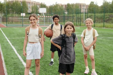 Aktif giyimli tatlı okul çocukları ve liseli kızlar spor sahasında ya da yeşil futbol sahasında boş vakitlerinde kameranın önünde durup sana bakıyorlar.