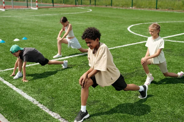 African American Schoolboy Activewear Doing Stretching Exercise Green Grass Stadium — Stock Photo, Image