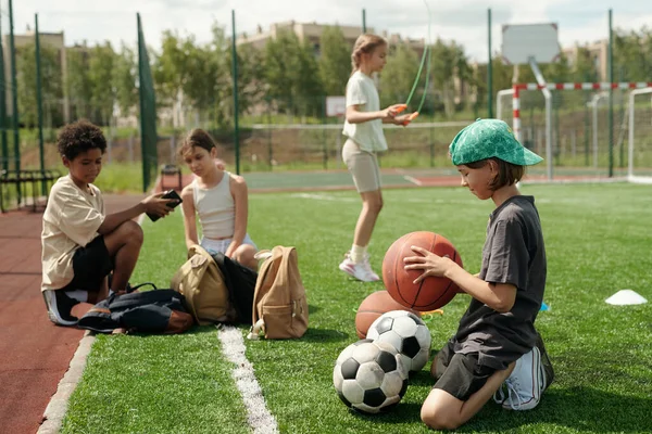 Πλευρική Άποψη Του Σχολιαρόπαιδο Activewear Επιλέγοντας Μπάλα Για Παιχνίδι Σπορ — Φωτογραφία Αρχείου