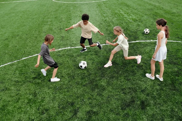 Grupp Interkulturella Skolbarn Efter Fotboll Medan Springer Längs Gröna Fotbollsplan — Stockfoto