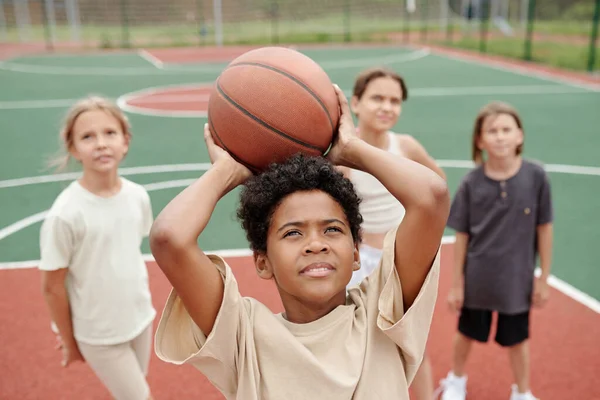 在学校比赛前的篮球训练中 非洲裔美国学生把头放在头上 把球扔进篮筐里 — 图库照片