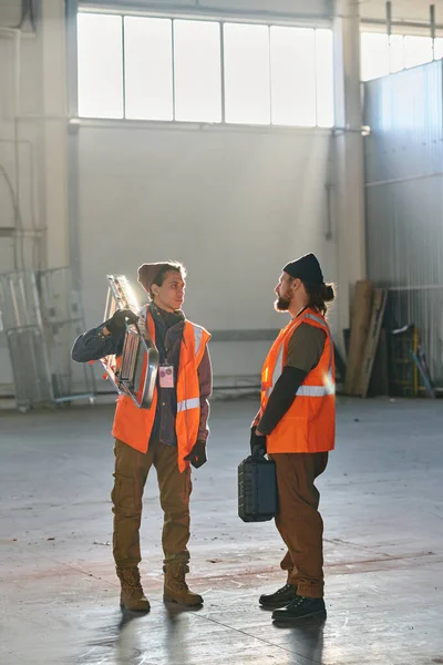 Dos Jóvenes Ingenieros Chaquetas Reflectantes Protectoras Discutiendo Algo Reunión Trabajo —  Fotos de Stock