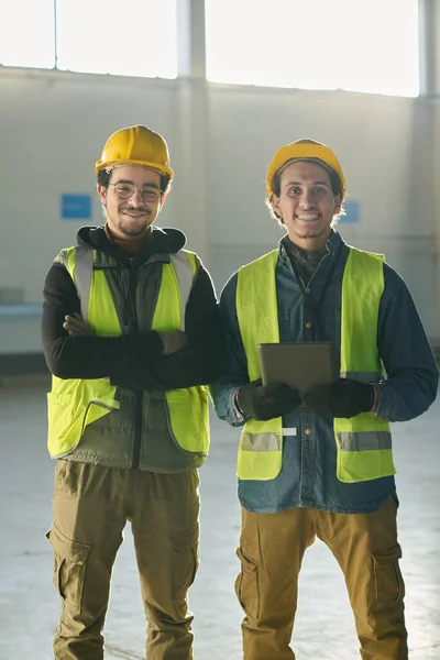 Dos Jóvenes Ingenieros Multiétnicos Sonrientes Pie Frente Cámara Almacén Iluminados —  Fotos de Stock