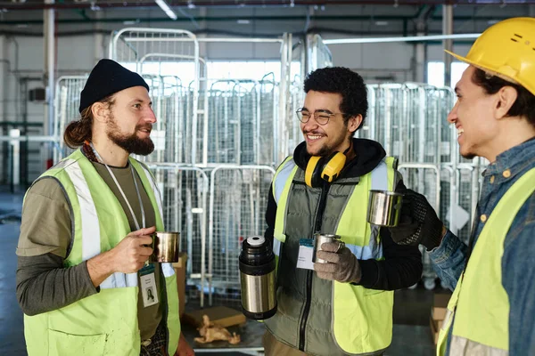Tres Jóvenes Trabajadores Felices Con Tazas Metálicas Caliente Conversando Mientras —  Fotos de Stock