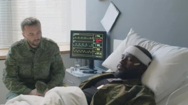 Üzgün asker, bilinci yerinde olmayan arkadaşının önünde yatıyor. Beyin hasarı var ve hastane yatağında yatıyor.