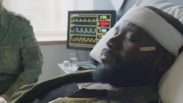 現代の軍病院で脳損傷を負った無意識のアフリカ系アメリカ人将校の閉じた肖像画 — ストック動画