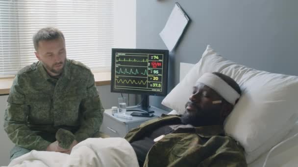 Trauriger Soldat Sitzt Vor Seinem Bewusstlosen Freund Mit Hirnverletzungen Krankenhausbett — Stockvideo