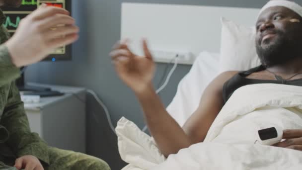 認知できない兵士と彼の負傷した同僚のスローモーションショットは 病院のベッドで握手をしている — ストック動画