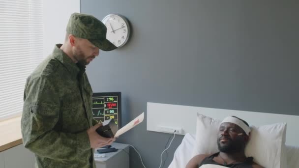 軍病院で負傷したアフリカ系アメリカ人兵士を訪問したコーカサス大尉は 彼に賞を祝福した — ストック動画