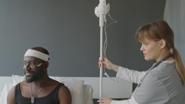 병원에서 아프리카계 미국인 환자를위한 요법을 시작하기 가방과 튜브가있는 코카서스 간호사 — 비디오