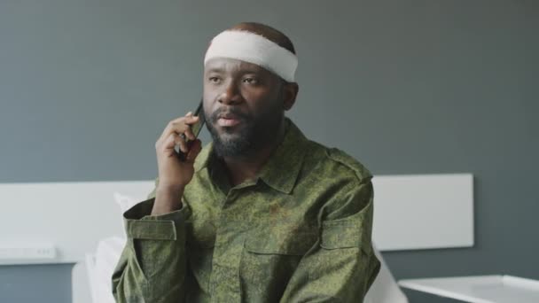 身穿迷彩服 身受枪伤的非裔美国军人坐在病房与家人或朋友通电话 — 图库视频影像