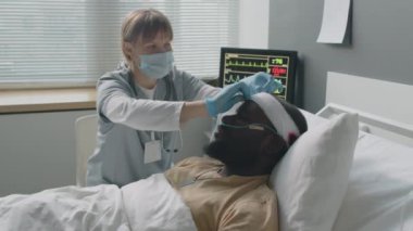 Kadın doktor, askeri hastanede başından yaralanan Afro-Amerikan askerleri için bandaj ve burun kanülünü onarıyor.
