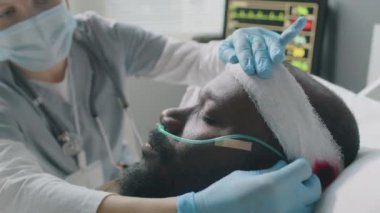 Kafa yaralanması geçiren Afro-Amerikan bir adam için doktor, bandaj ve burun kanülünü kontrol ve onarıma odaklı seçici odaklanma.