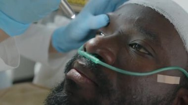 Doktorun beyin hasarı olan Afrikalı Amerikalı hastanın göz bebeği tepkisini kontrol ederken yakın plan fotoğrafı.