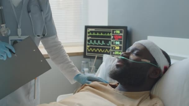 アフリカ系アメリカ人の患者の状態をチェックし 医療カードでメモを作る認識できない女性医師 — ストック動画