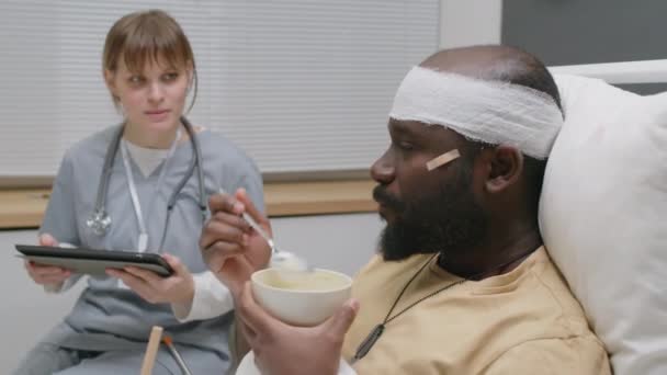 Selektywne Ujęcie Rannego Afroamerykanina Jedzącego Posiłek Odpowiadającego Pytania Lekarzy Jego — Wideo stockowe