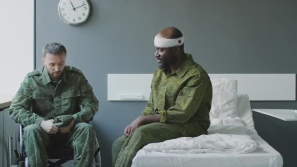 軍病院の会話室に座って戦場で負傷した民族的に多様な兵士 — ストック動画