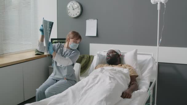 Kafkasyalı Kadın Doktor Yaralı Siyah Hastaya Beyin Röntgeni Gösteriyor Tedavi — Stok video