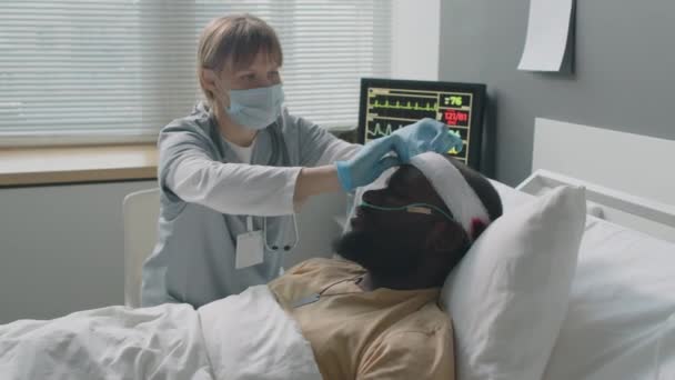軍病院で頭部負傷したアフリカ系アメリカ人兵士のための包帯と鼻腔を固定する女性医師 — ストック動画