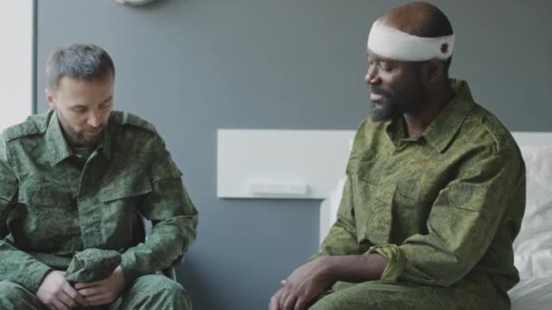 治療について話す軍病院の部屋に座って頭部に負傷した民族的に多様な兵士の中型ショット — ストック動画