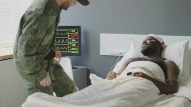 Neşeli Kafkasyalı asker askeri hastanedeki siyah arkadaşını ziyaret ediyor, onu el sıkışarak selamlıyor.